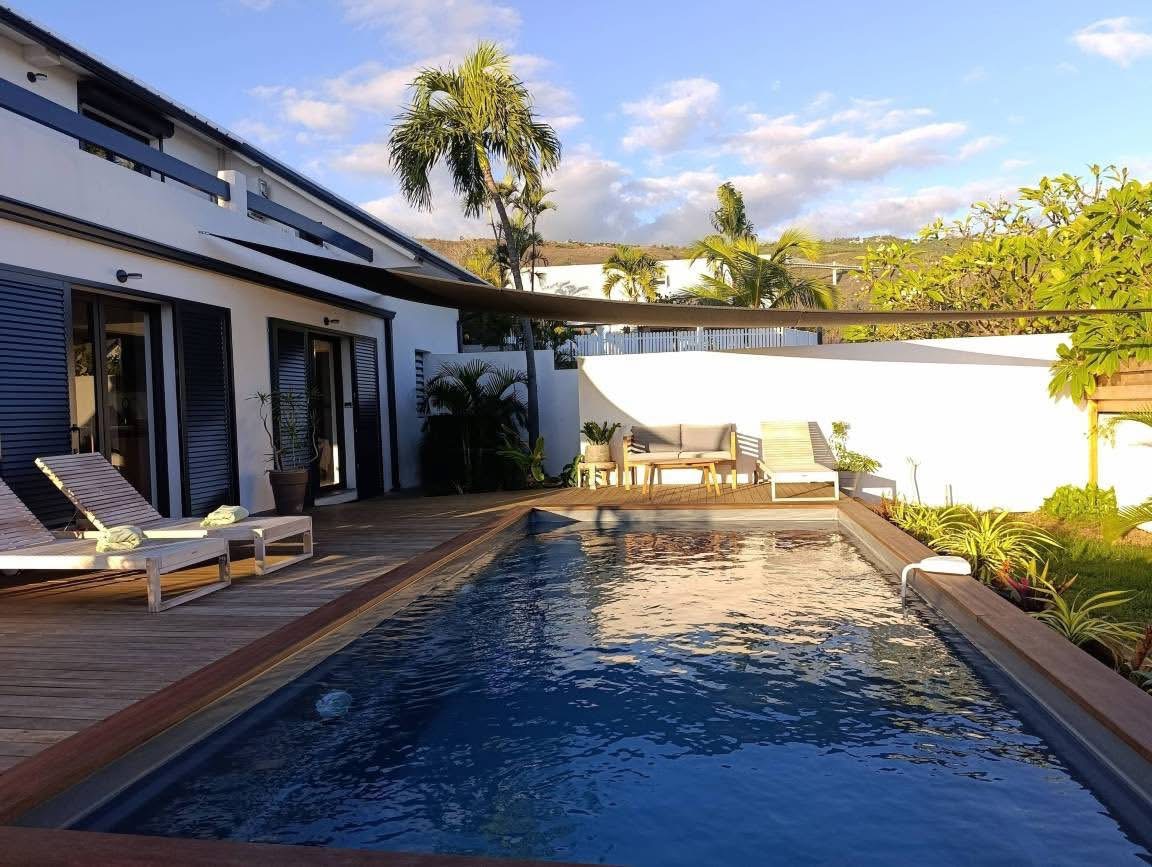 Longue piscine et façade de la villa en fin de journée